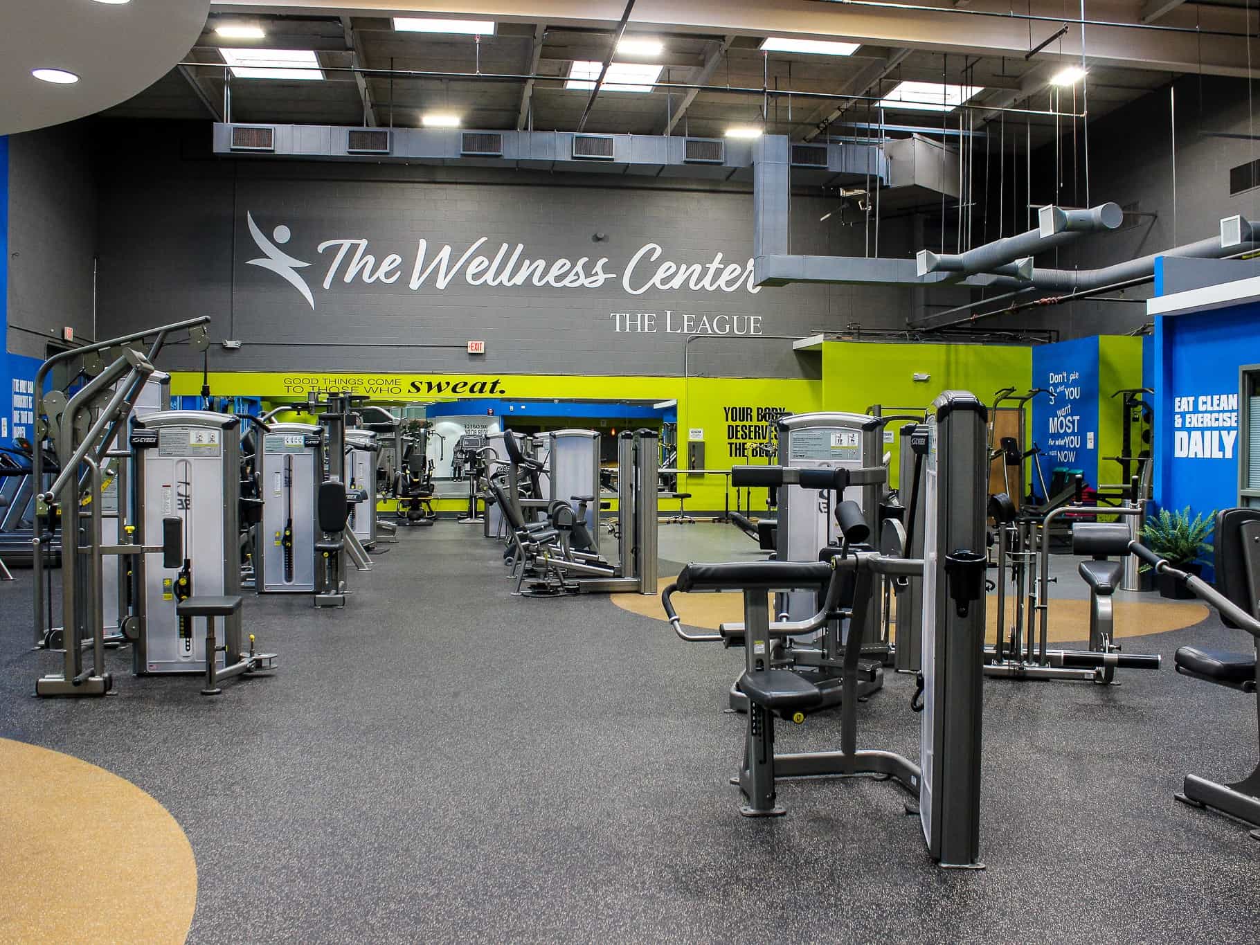 A gym with accessible equipment, ample natural lighting, and motivating lime green accent walls.