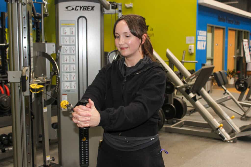 A woman wearing all black using gym equipment